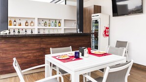 A modern kitchen with a bar area, white cabinetry, and a large TV on the wall. - Hotel Nube, Puebla Centro (Puebla)