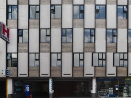 Een modern gevelontwerp met een raster van ramen en gepatteerde panelen.