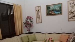 Un salon avec un canapé, une table basse et un fauteuil. Trois tableaux encadrés sont accrochés au mur.