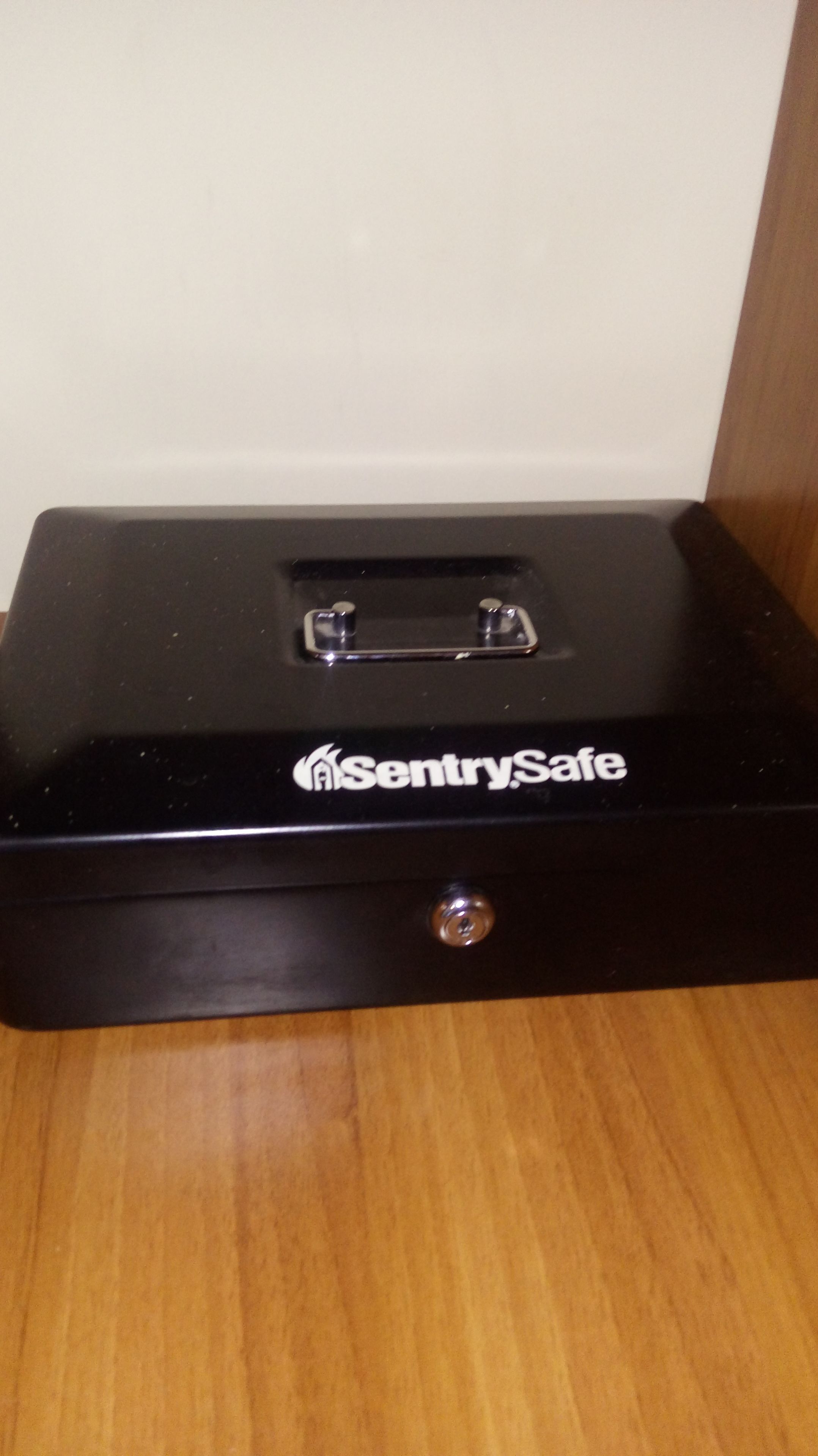 A black metal safe with a handle and a lock, labeled "SentrySafe."