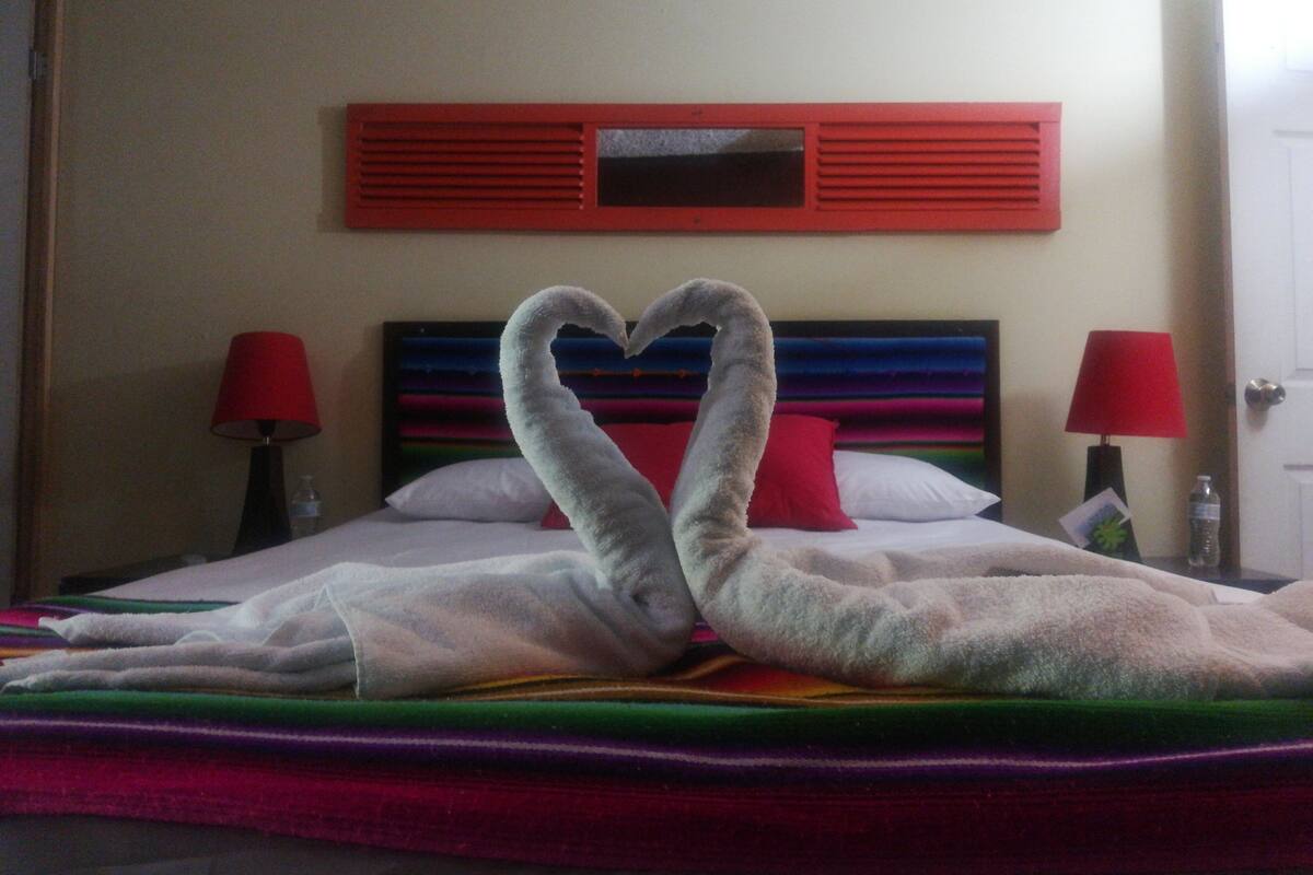 Ein Bett mit einer herzförmigen Handtuchgestaltung und einer farbenfrohen Tagesdecke.