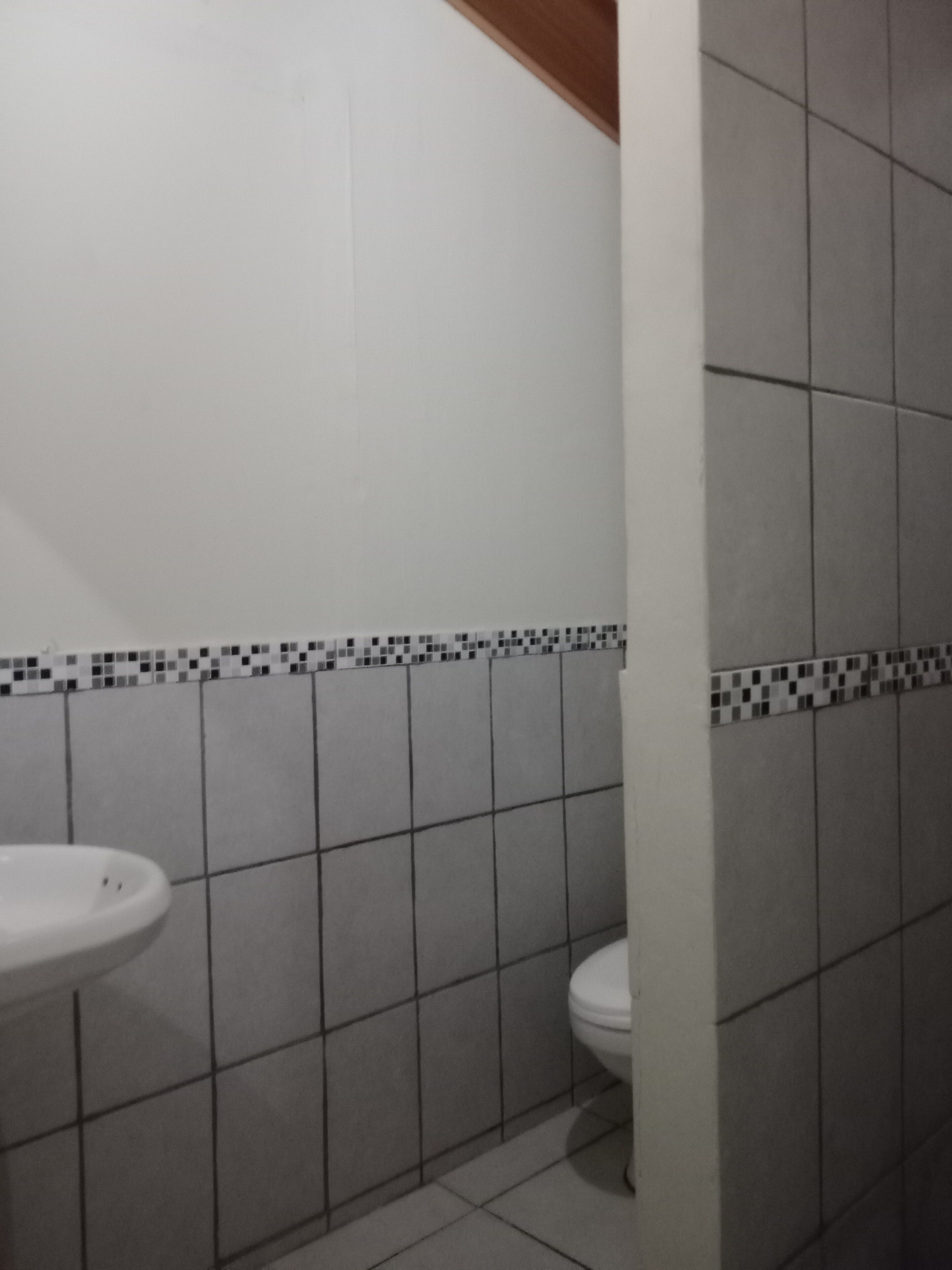 A bathroom with a white sink, toilet, and tiled walls.