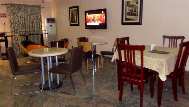 A dining area with a round table, chairs, and a television mounted on the wall. - AES Luxury Apartments (Lagos)