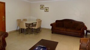 A living room with a dining table, chairs, a sofa, and a coffee table. - AES Luxury Apartments (Lagos)