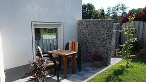 Eine Terrasse mit Tisch und Stühlen, einem Blumentopf und einer Steinmauer.