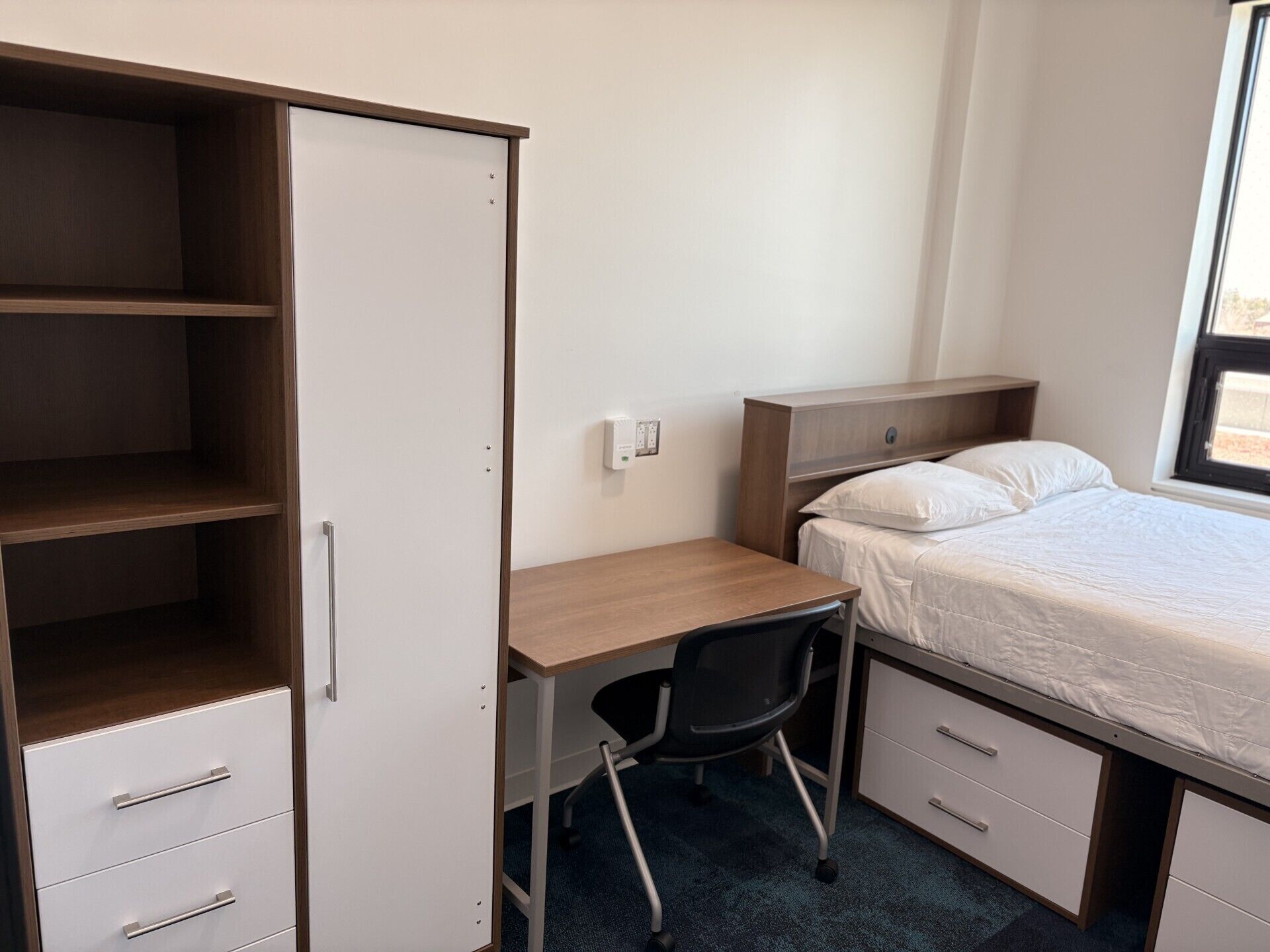 Una habitación pequeña con cama, escritorio y armario.