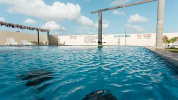 Una piscina al aire libre, sombrillas, sillones reclinables de piscina