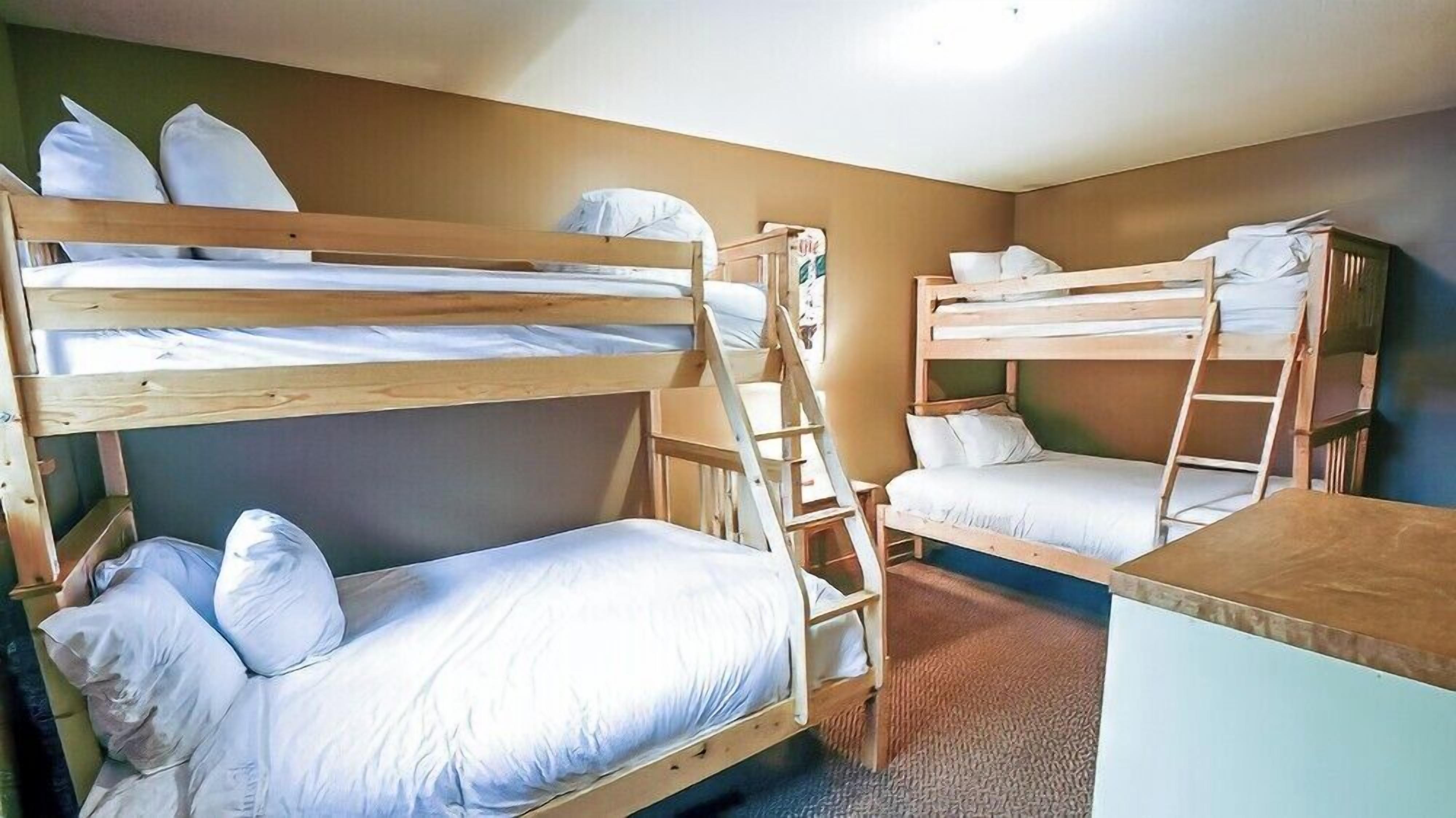 Une chambre avec un lit superposé, une échelle, un bureau et une chaise.