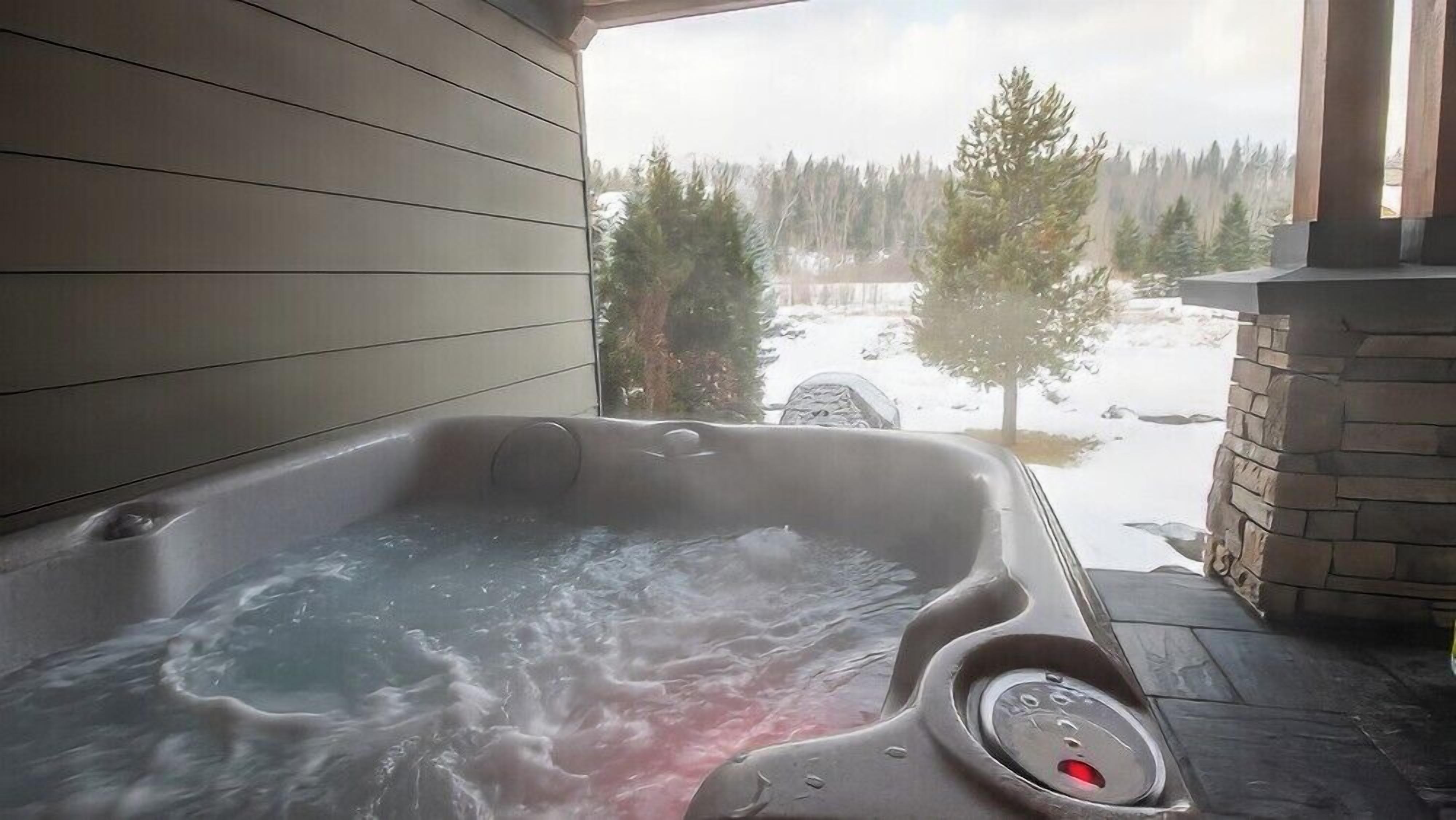 A hot tub with a view of a snowy landscape and trees.