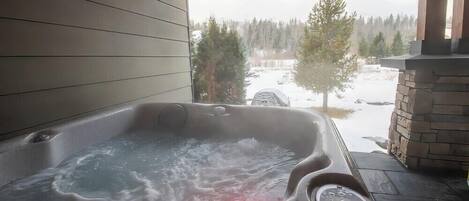 A hot tub with a view of a snowy landscape and trees.