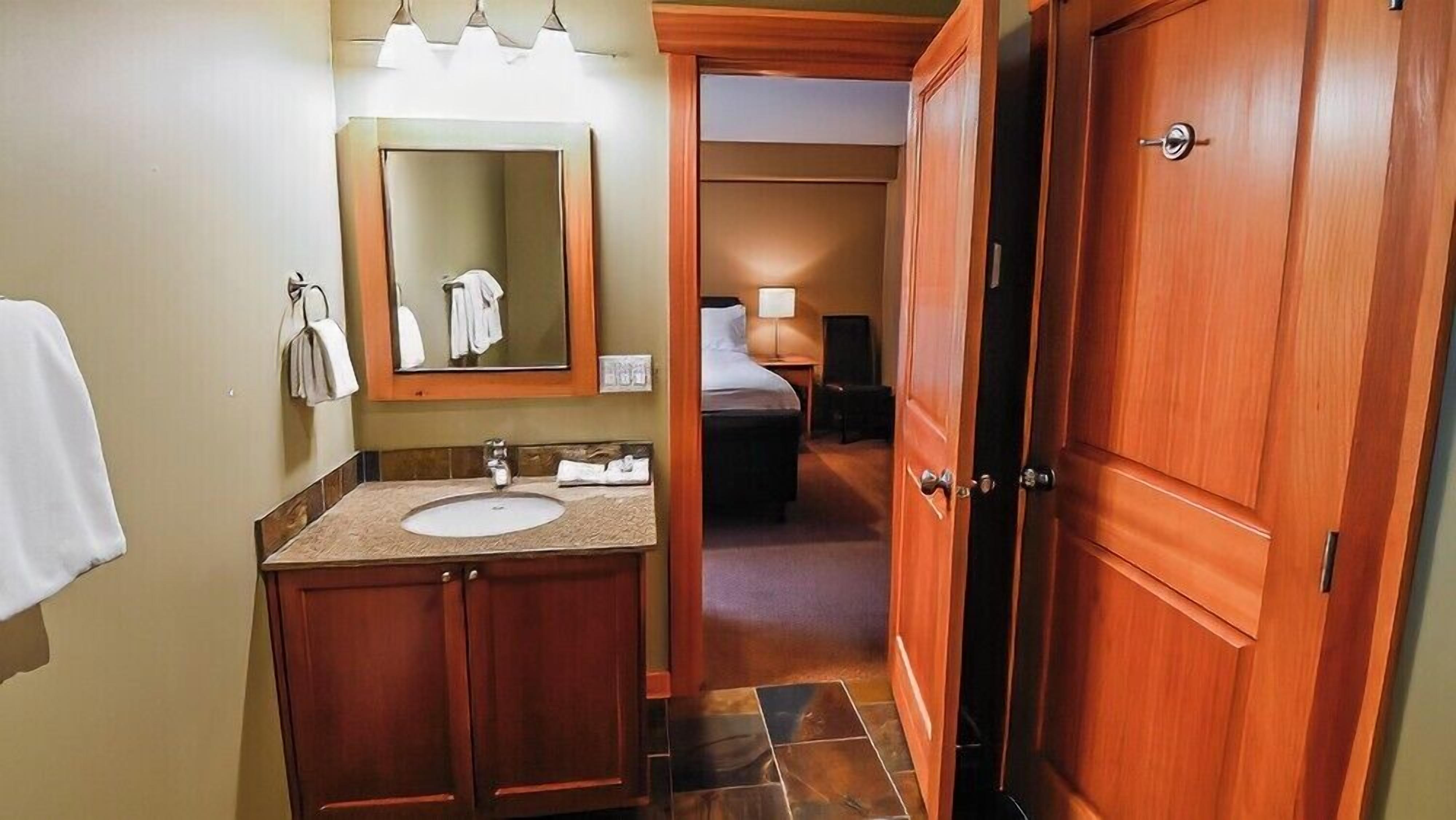 A hotel bathroom with a sink, mirror, and wooden door.