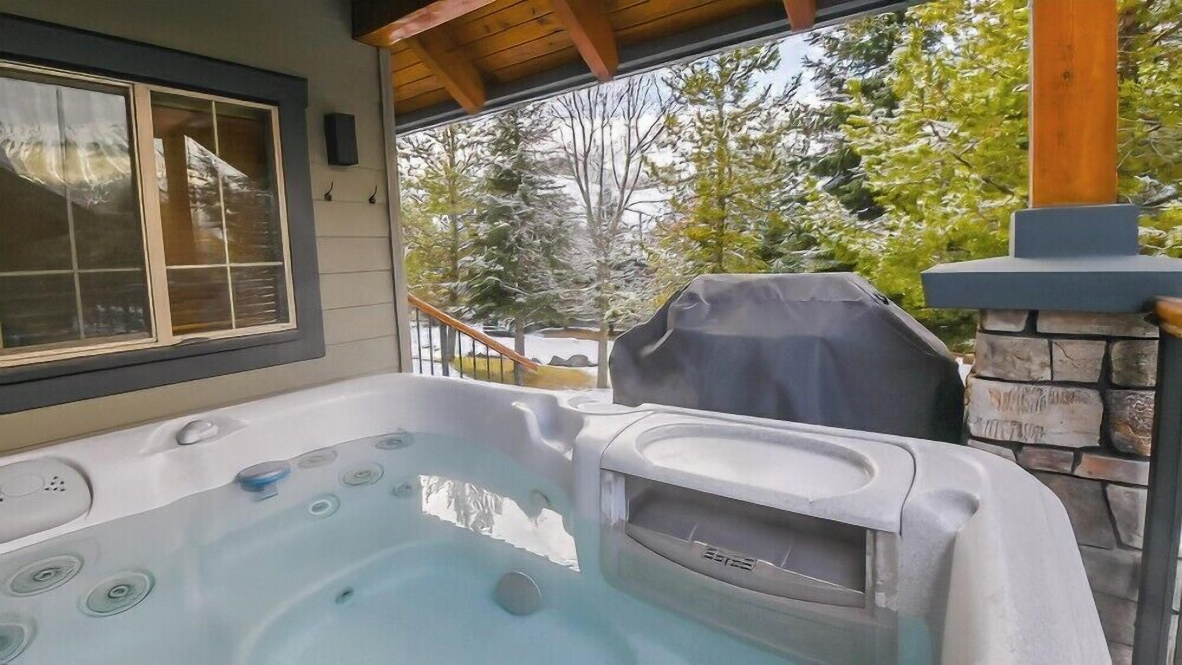 Un bain à remous avec une cheminée en pierre et une vue sur les arbres.
