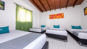 A hotel room with three single beds, each with a teal pillow and a grey bedspread. The room has a wooden ceiling, white walls, and a green patterned curtain. - Ayenda Villas de San Juan (Medellín)