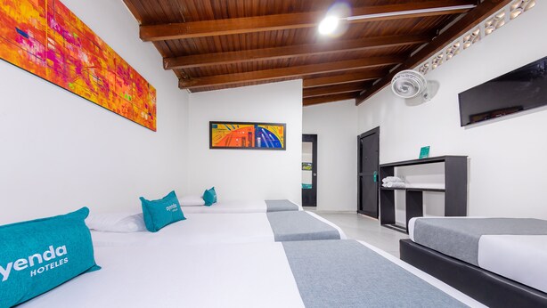 A hotel room with two beds, a large abstract painting, a television, and a ceiling fan. - Ayenda Villas de San Juan (Medellín)