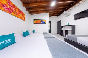 A hotel room with two beds, a large abstract painting, a television, and a ceiling fan. - Ayenda Villas de San Juan (Medellín)