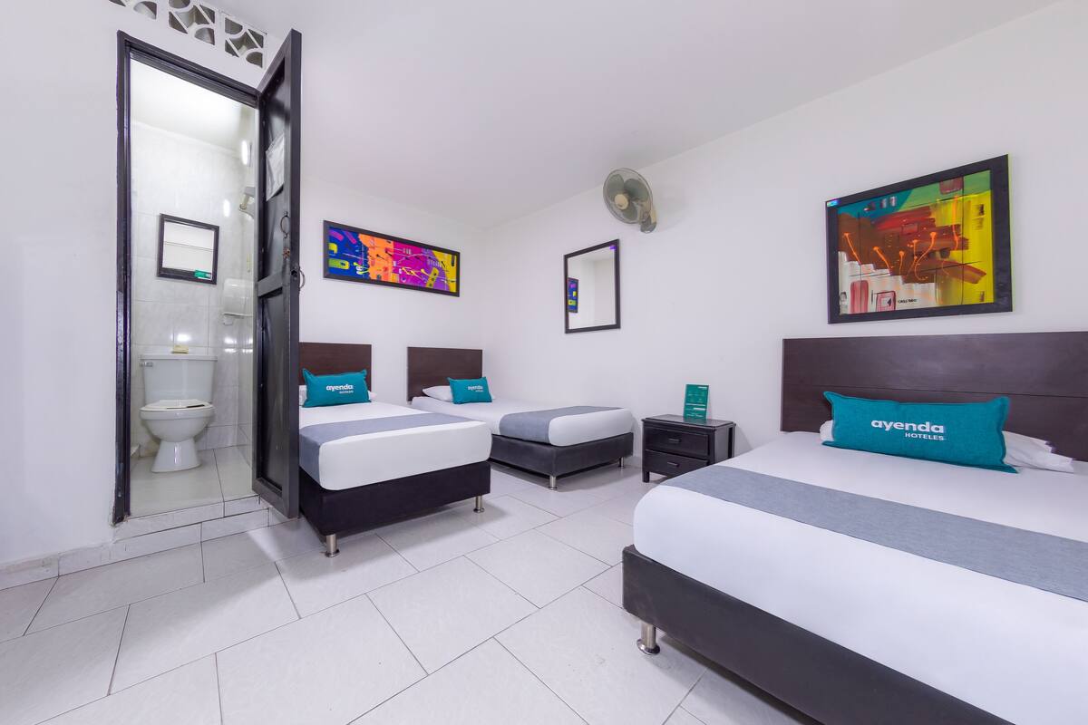 Ein Hotelzimmer mit zwei Betten, einem Badezimmer und einem großen Fenster.