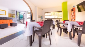 A dining area with tables and chairs, a sofa, and a staircase leading to an upper level. - Ayenda Villas de San Juan (Medellín)