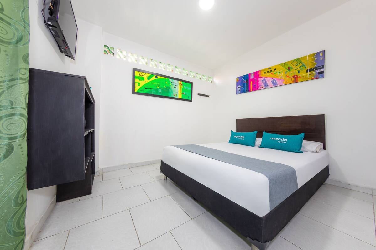 Ein Hotelzimmer mit einem Bett, einem Kleiderschrank und zwei an der Wand befestigten Kunstwerken.