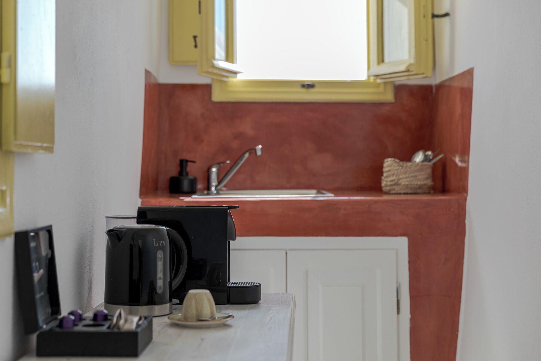 A compact kitchen with a sink, a coffee maker, and a small window above the countertop.