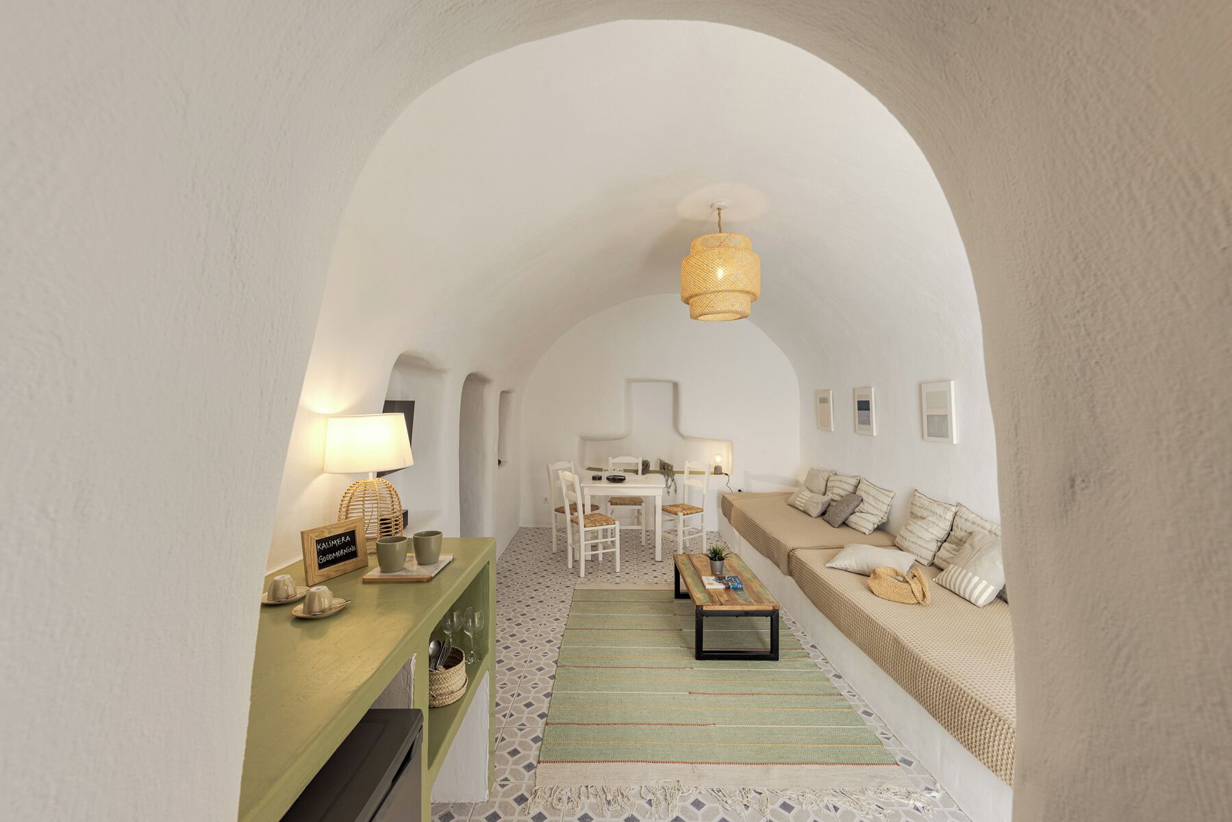A cozy interior with a dining area, a sofa, and a hanging light fixture.