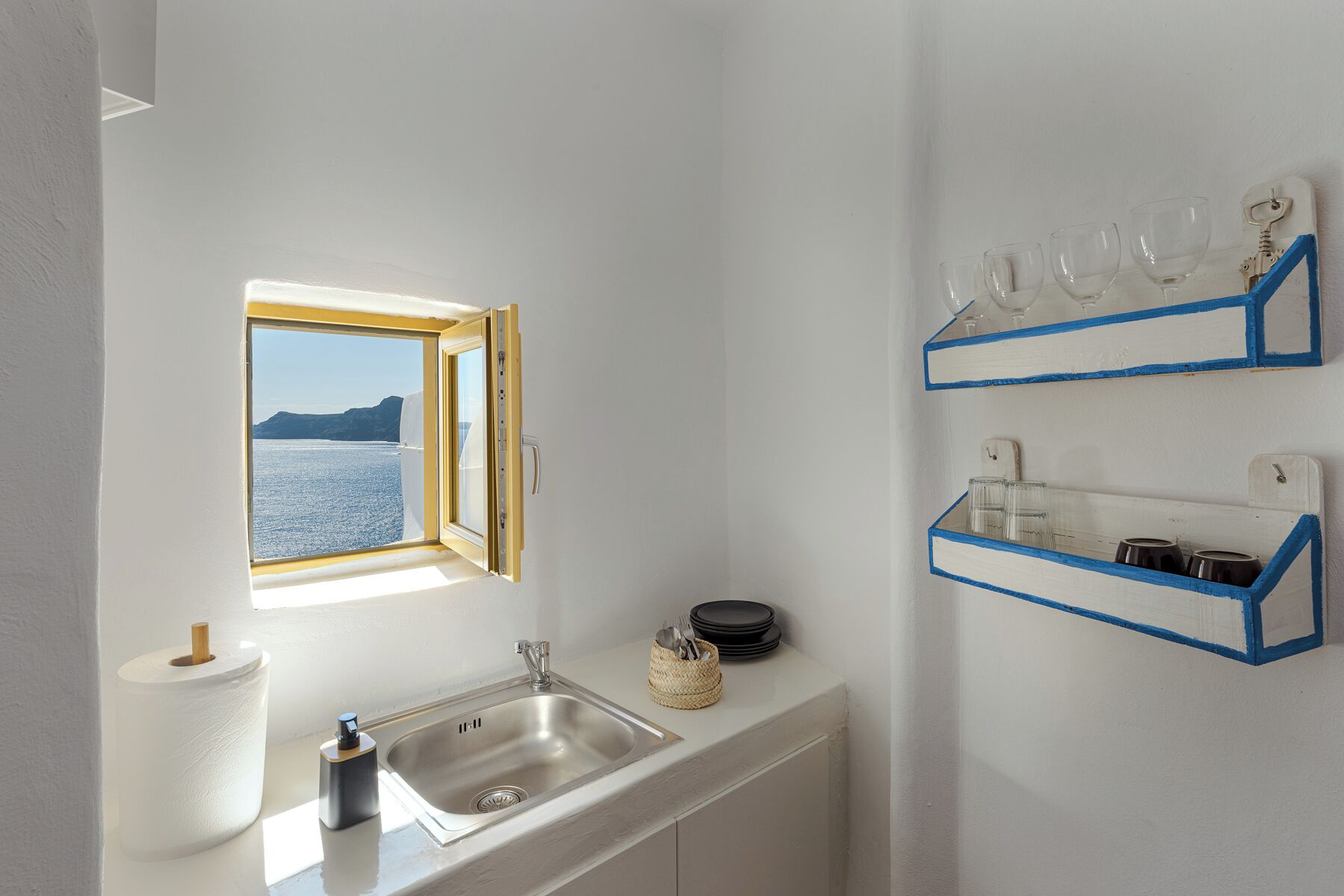 A kitchen with a window, a sink, and shelves with glasses and dishes.