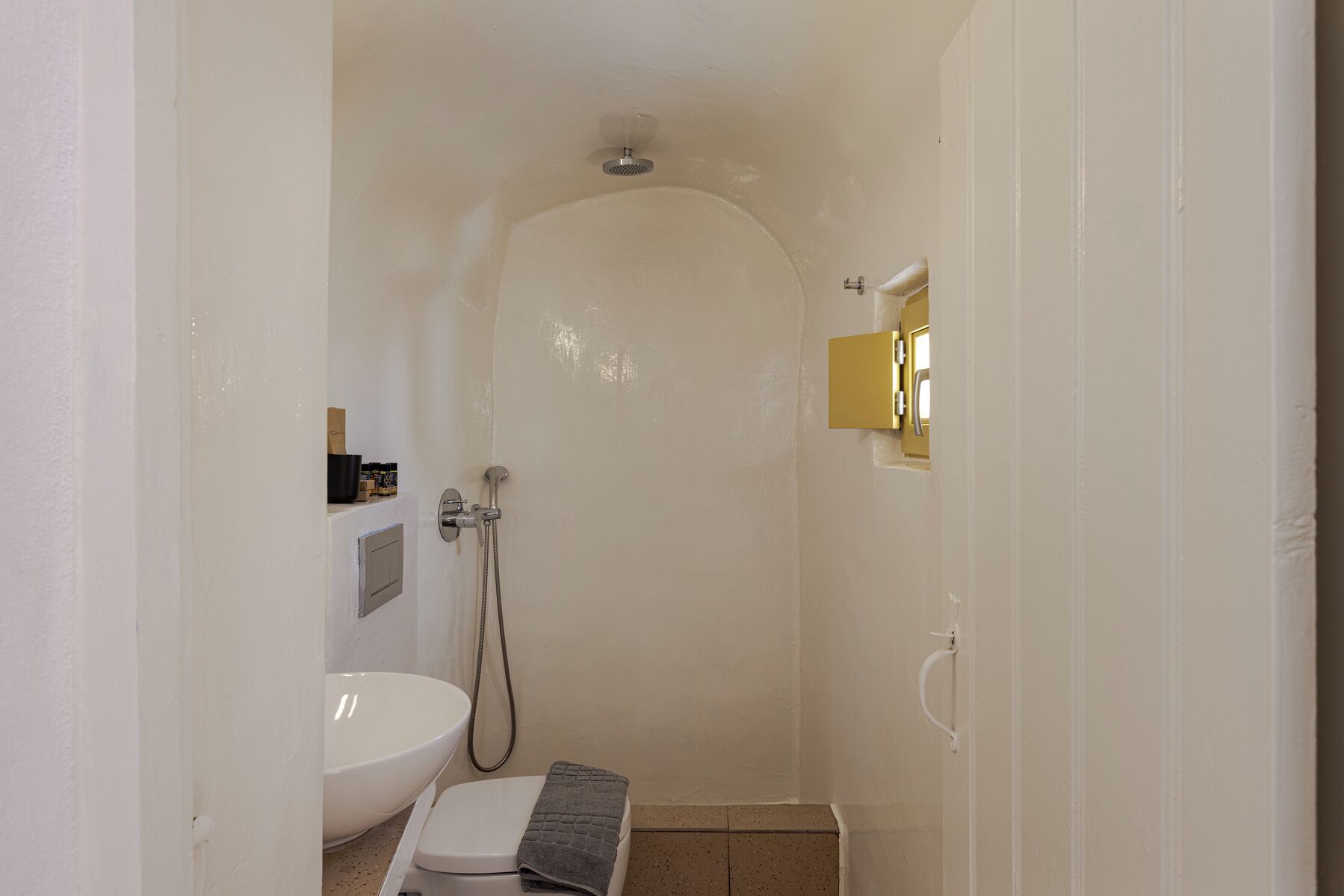 Un baño pequeño y blanco con ducha, inodoro y lavabo.