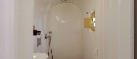Un baño pequeño y blanco con ducha, inodoro y lavabo.