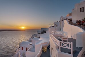 Un edificio costero de arquitectura blanca, con una escalera y vistas al mar al atardecer.