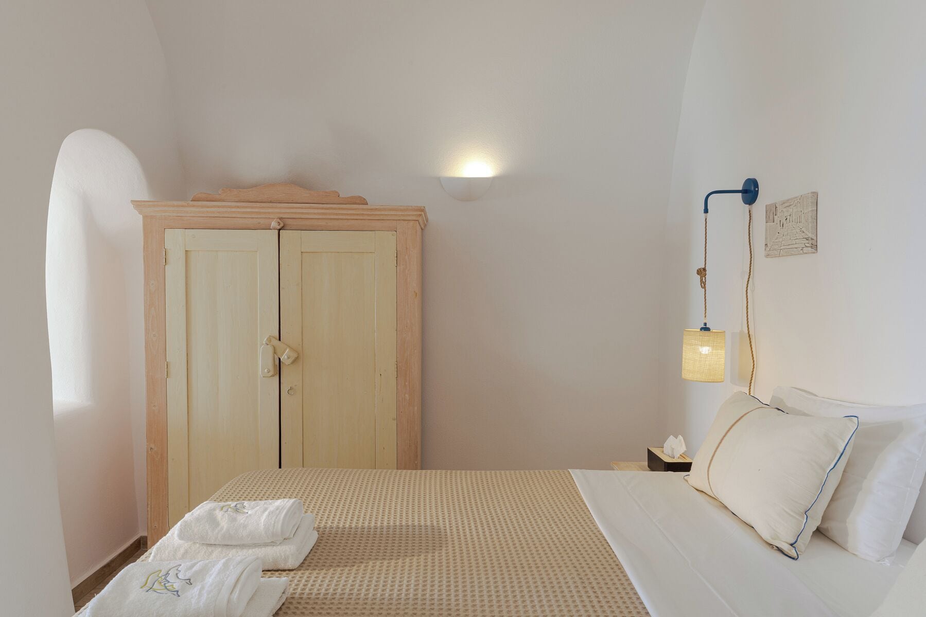 Een slaapkamer met een bed, een kledingkast, een bedlampje en een aan de muur hangend schilderij.