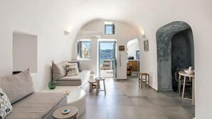 A modern interior with a sofa, a dining table, and a kitchen area. - Just Blue (Santorini)