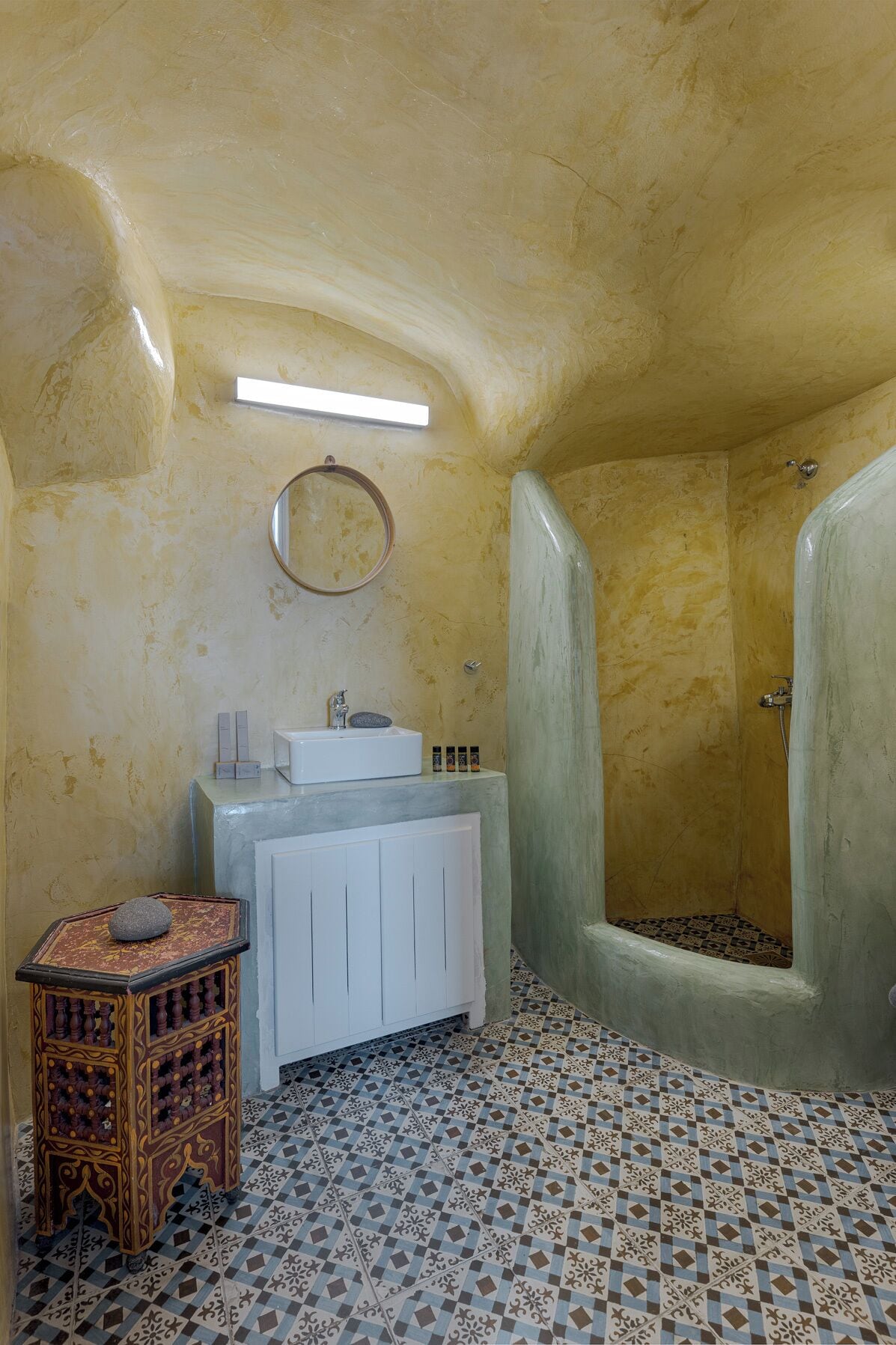 Un baño con bañera, lavamanos, espejo y baldosas de suelo estampadas.