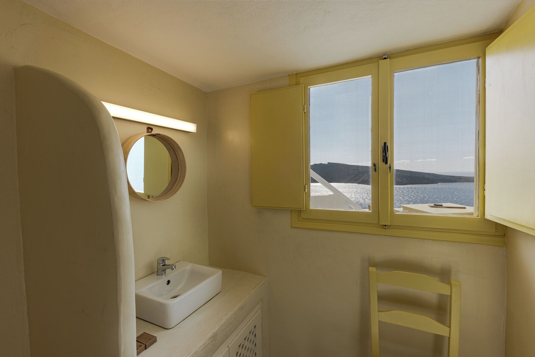 Ein Badezimmer mit Waschbecken, Spiegel und Fenster mit Meerblick.