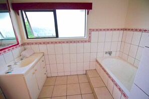 Un baño con lavamanos, espejo, ventana y bañera.