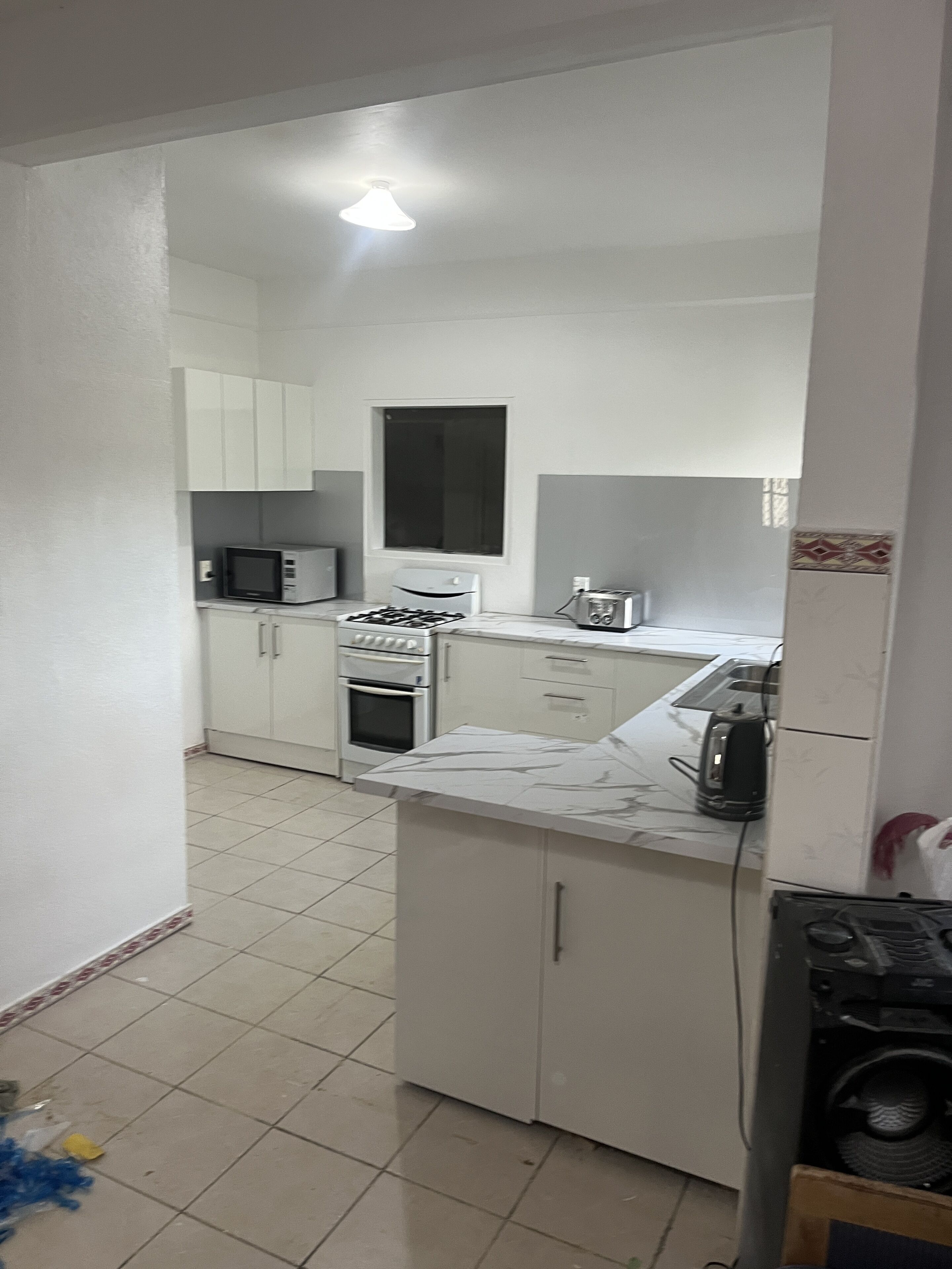 A compact kitchen with white cabinets, a microwave, an oven, and a toaster.