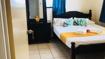 Una habitación de hotel con cama, mesita de noche, espejo y ventana con cortinas.