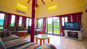 Una sala de estar con un sofá, sillas, un televisor y una mesa con un florero.