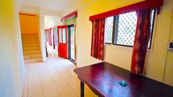 A corridor with a wooden bench, tiled floor, and a door leading to another room.