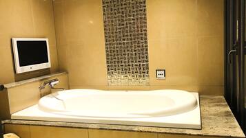 A modern bathroom with a freestanding bathtub, a wall-mounted TV, and a patterned tile backsplash.