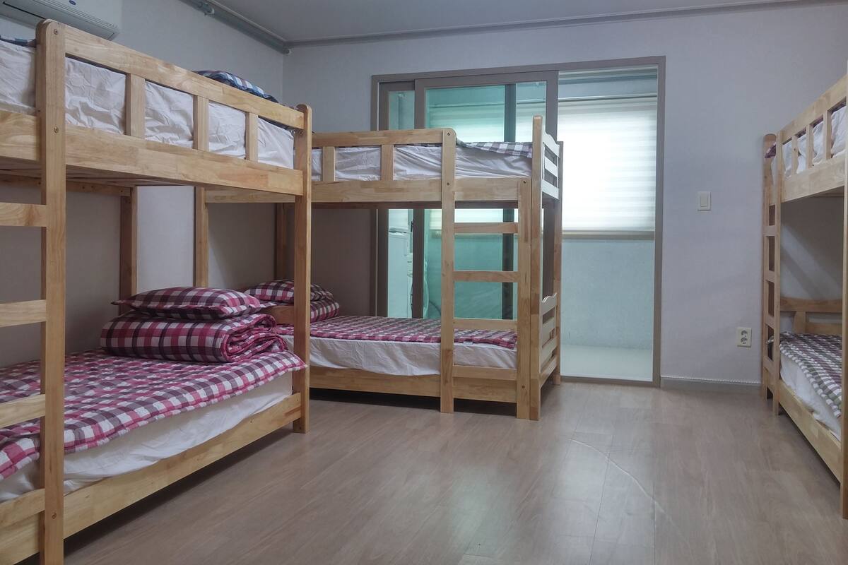 Quarto com três beliches, uma porta de correr e ar condicionado instalado no teto.