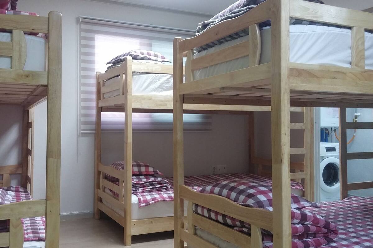 Quarto com três beliches, cada um com cobertor e travesseiro xadrez.