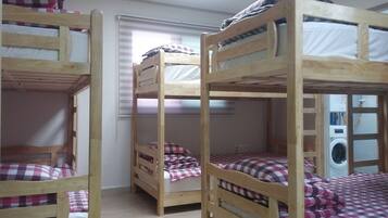 Una habitación con tres literas, cada una con una manta y almohada a cuadros.