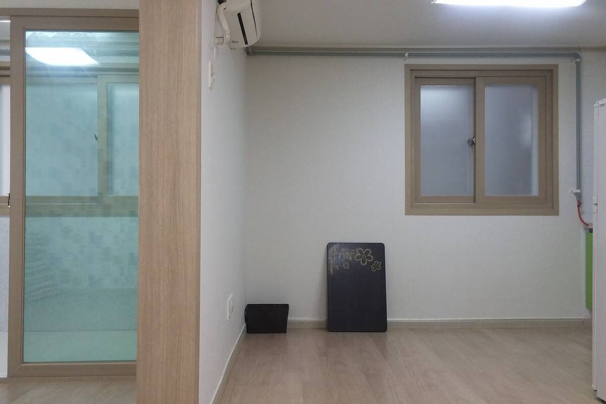 Quarto com porta de vidro deslizante, um pequeno objeto preto no chão e janela com painel fosco.
