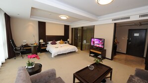 Une chambre d’hôtel comprenant un lit, une télévision, un bureau, une chaise, une table basse et une plante.