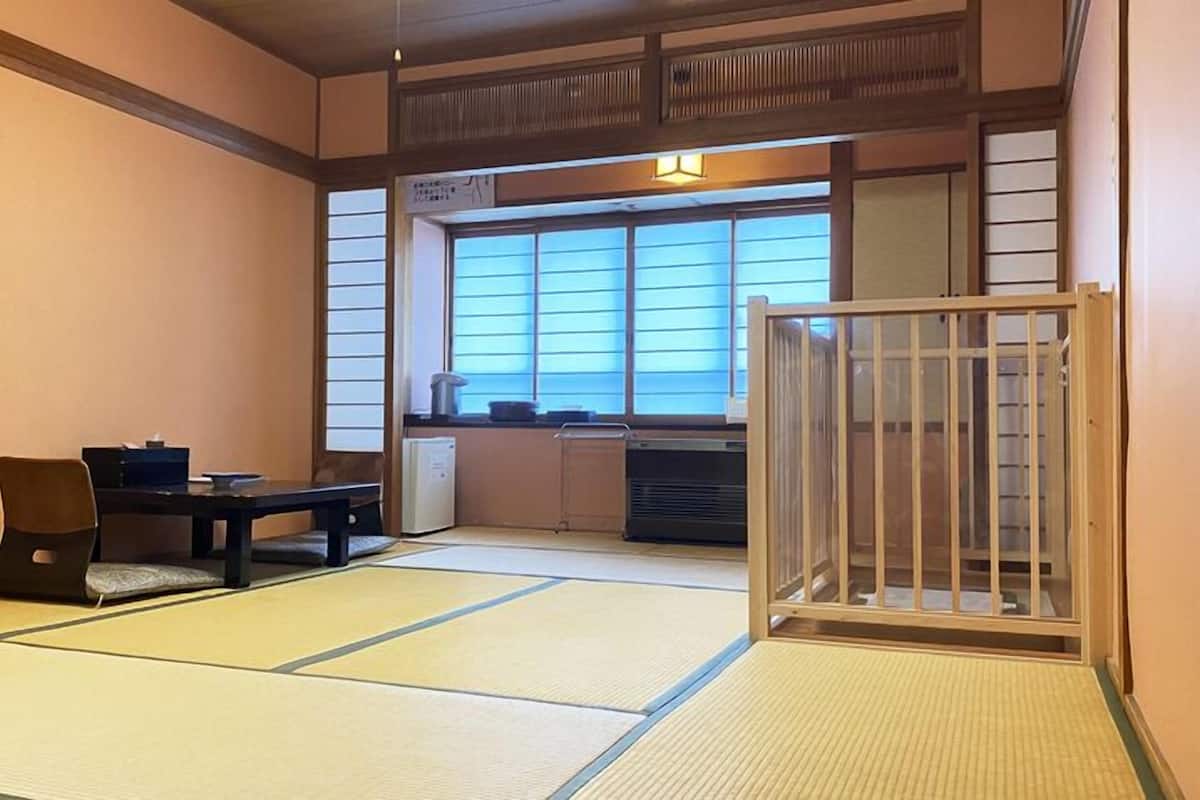 Una habitación japonesa tradicional con suelo de tatami, una mesa baja y un puertas correderas.