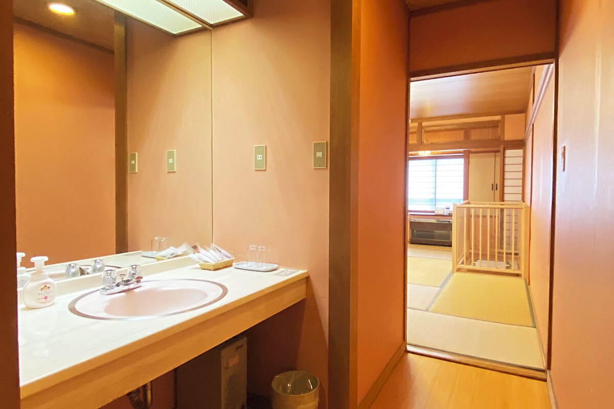 A bathroom with two sinks, a mirror, and a trash can.