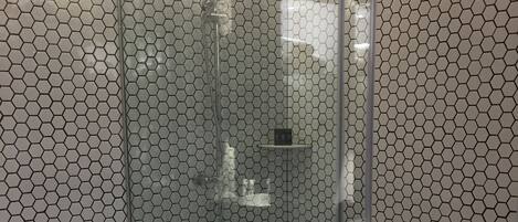 A bathroom with a glass-enclosed shower, a toilet, and a towel rack.