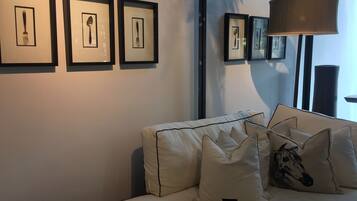 En moderne stue med sofa, indrammet kunst og en stor gulvlampe.