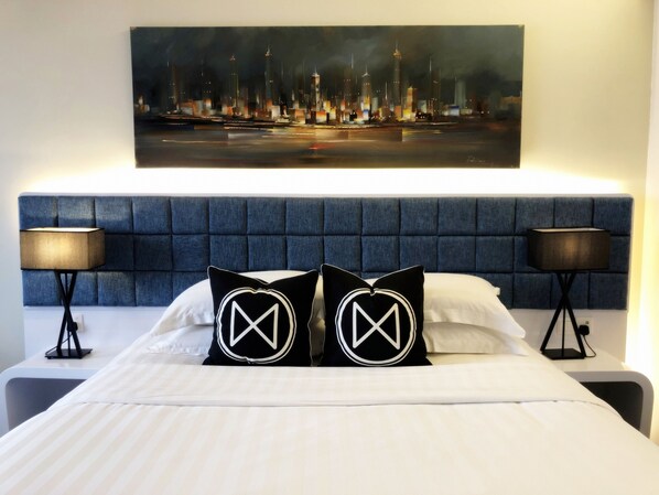 Habitación de hotel con una cama grande, dos mesitas de noche y un cuadro de paisaje urbano sobre la cama.