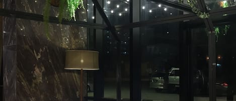 A modern interior with a white sofa, a marble wall, and hanging plants.