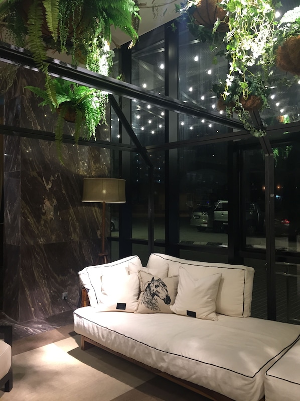 Un interior moderno con un sofá blanco, una pared de mármol y plantas colgantes.